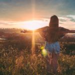 woman-stands-on-mountain-over-field-under-cloudy-sky-at-847483